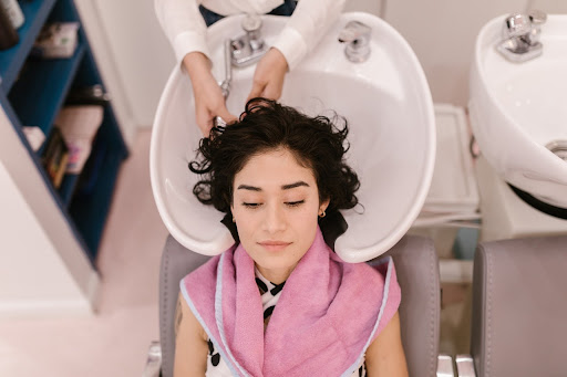 woman with dark hair getting her hair washed in a sink