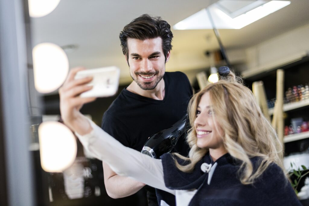 Cosmetologist and client making small talk and selfies