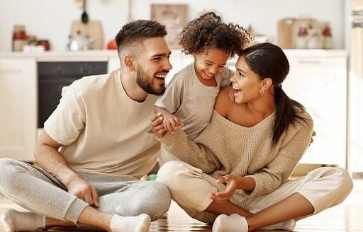 woman with a man smiling with a child palying with them