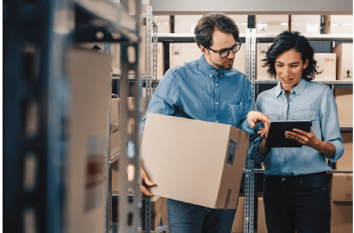 man and woman in a warehouse looking at an ipad