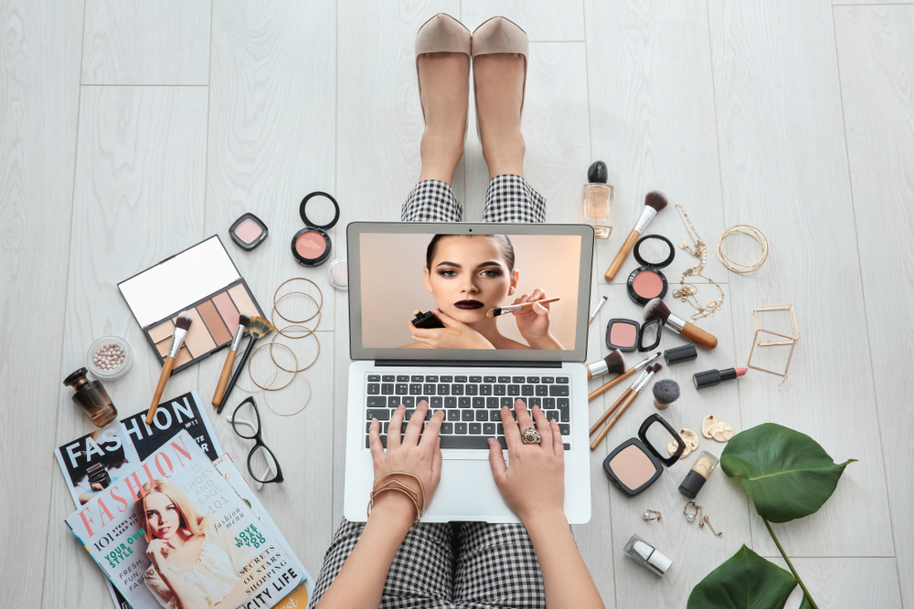 women at a laptop with makeup surrounding her